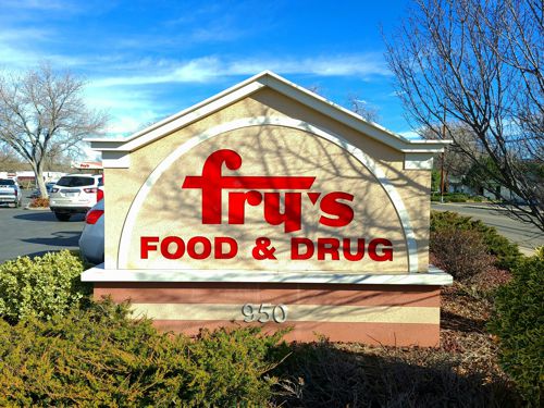 A sign for frys food and drug in front of bushes