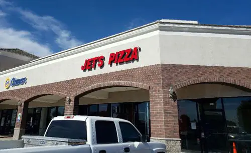 Jets Pizza outlet with a vehicle parked on it